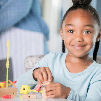 young girl smiling playing with blocks and sticks